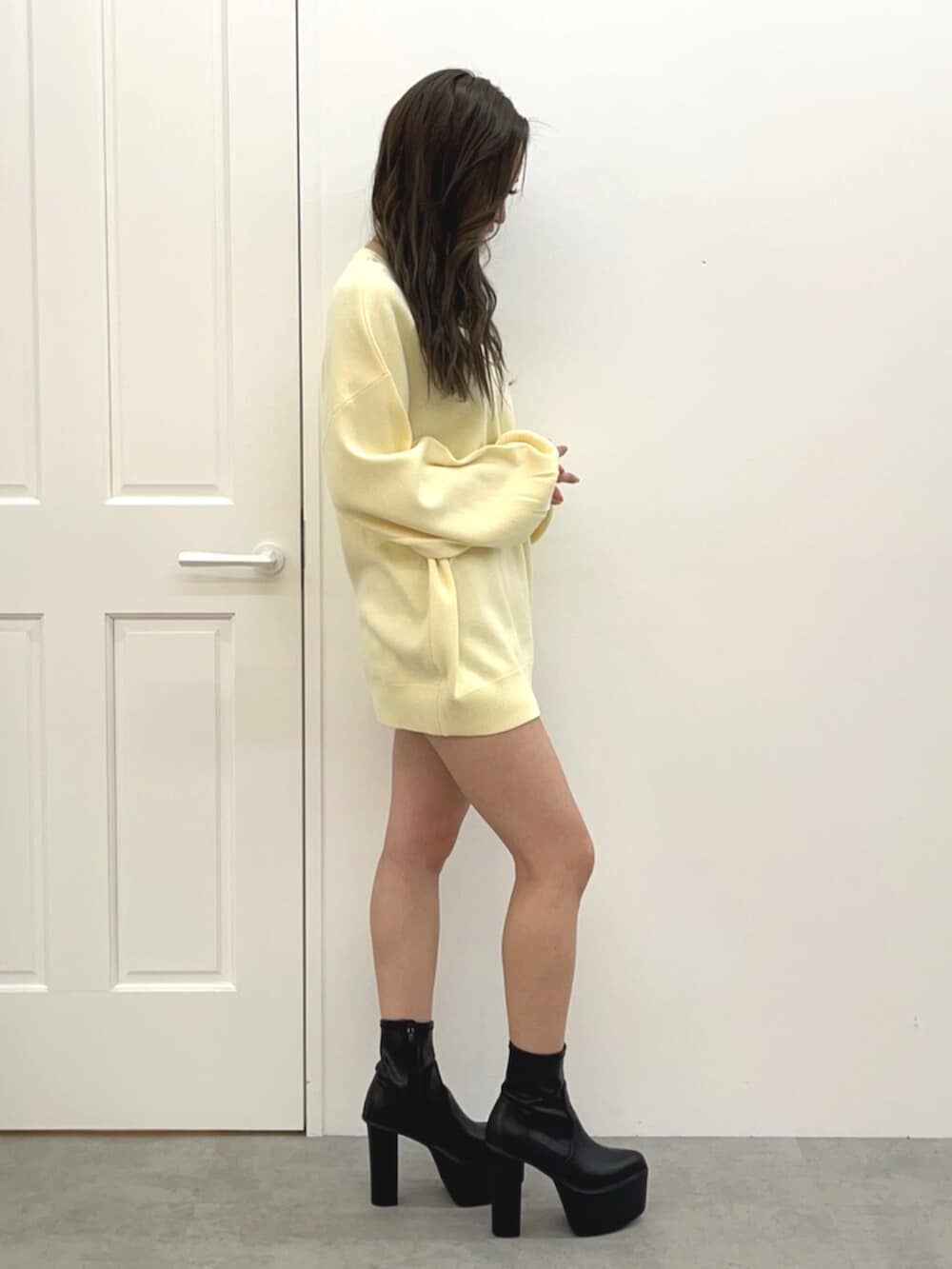 ブラック系のブーツ、ブルー系のデニムスカート、イエロー系のニット/セーターを着用したレディースの冬コーディネートの2枚目の写真