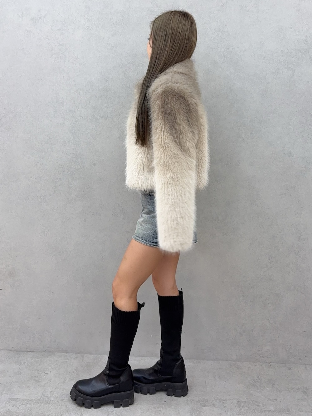 ホワイト系のニット/セーター、ブルー系のデニムスカート、ブラック系のブーツを着用したレディースの秋コーディネートの2枚目の写真