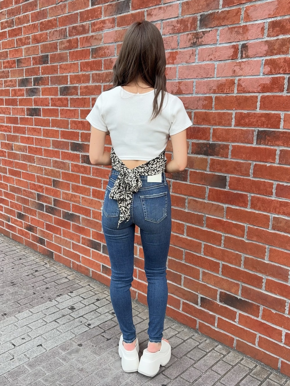 ホワイト系のTシャツ/カットソー、ブルー系のデニムパンツ、ホワイト系のサンダルを着用したレディースの夏コーディネートの3枚目の写真