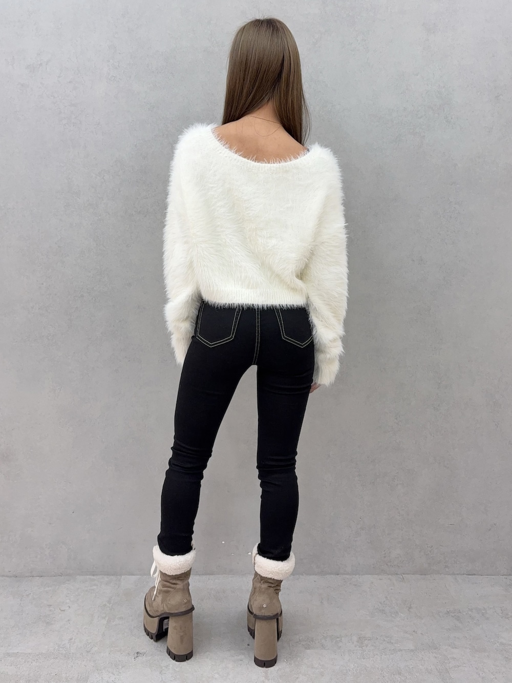 ブラック系のデニムパンツ、ベージュ系のブーツ、ホワイト系のニット/セーターを着用したレディースの秋コーディネートの3枚目の写真