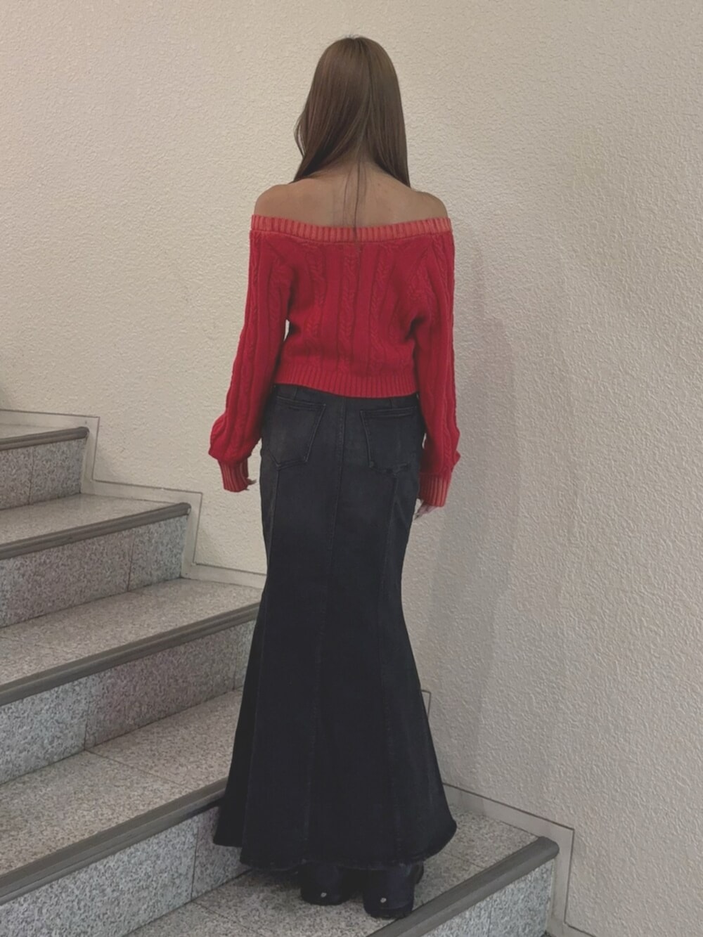 ブラック系のブーツ、レッド系のニット/セーター、ブラック系のデニムスカートを着用したレディースの秋コーディネートの3枚目の写真