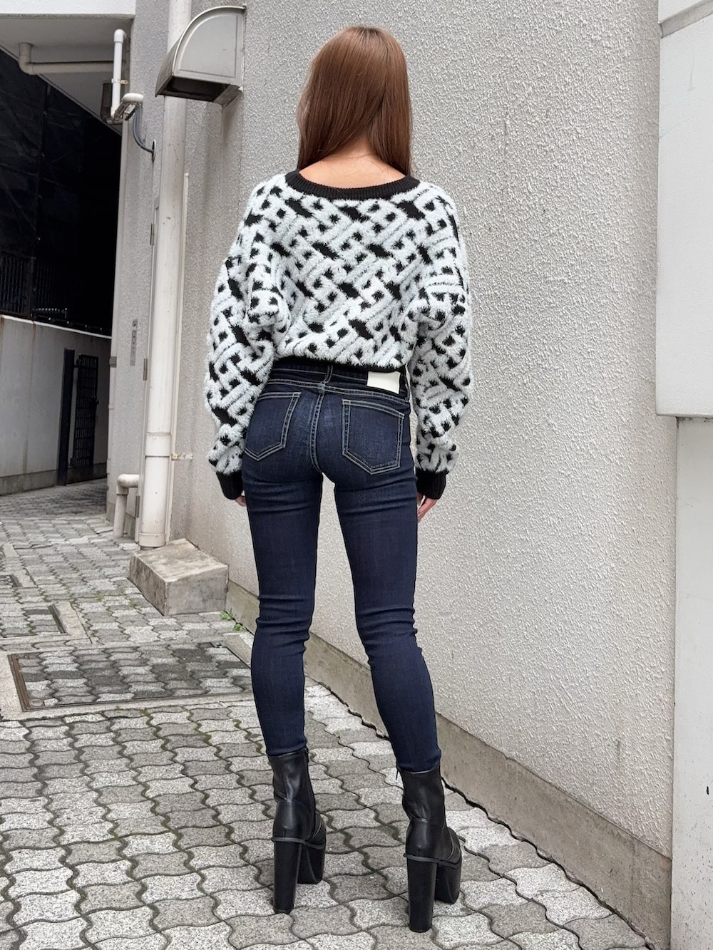 ブラック系のニット/セーター、ブルー系のデニムパンツ、ブラック系のブーツを着用したレディースの秋コーディネートの3枚目の写真