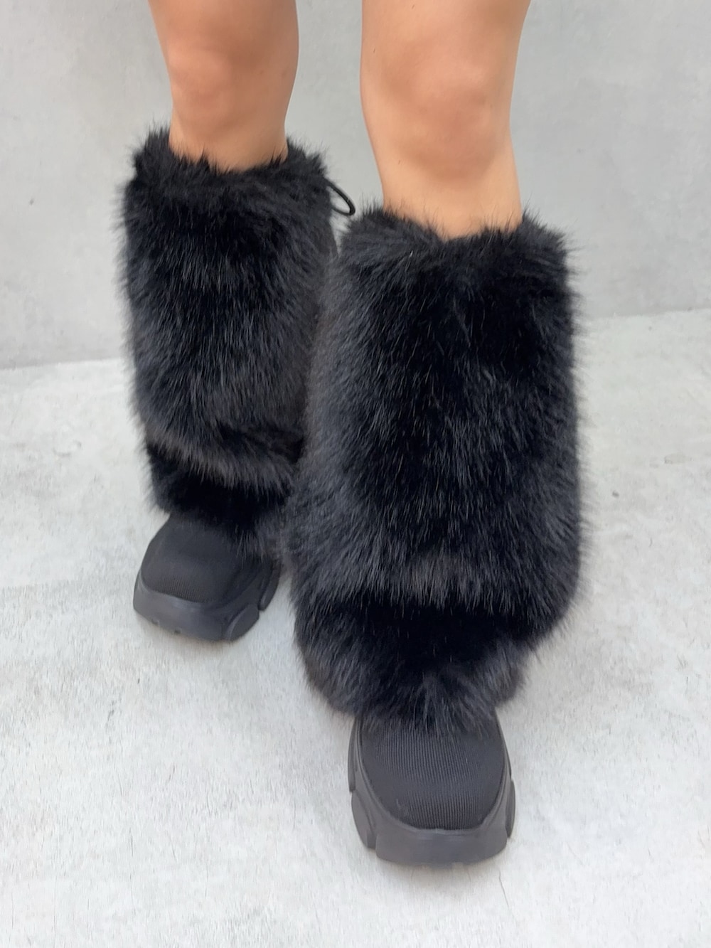 ブラック系のニット/セーター、ブルー系のデニムスカート、ブラック系のブーツを着用したレディースの秋コーディネートの5枚目の写真