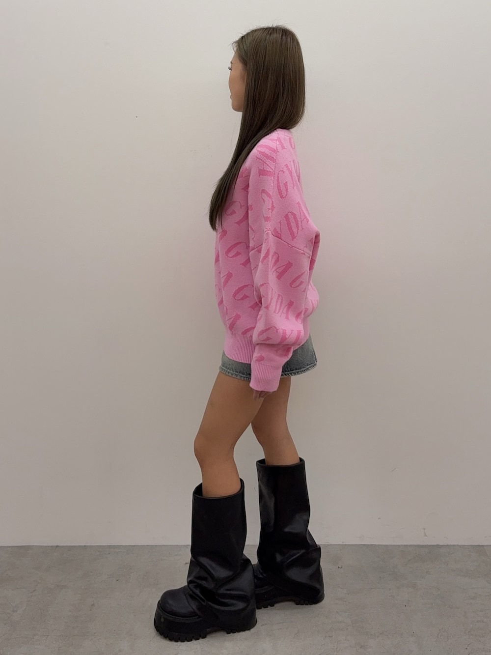 ピンク系のニット/セーター、ブルー系のデニムスカート、ブラック系のブーツを着用したレディースの秋コーディネートの2枚目の写真