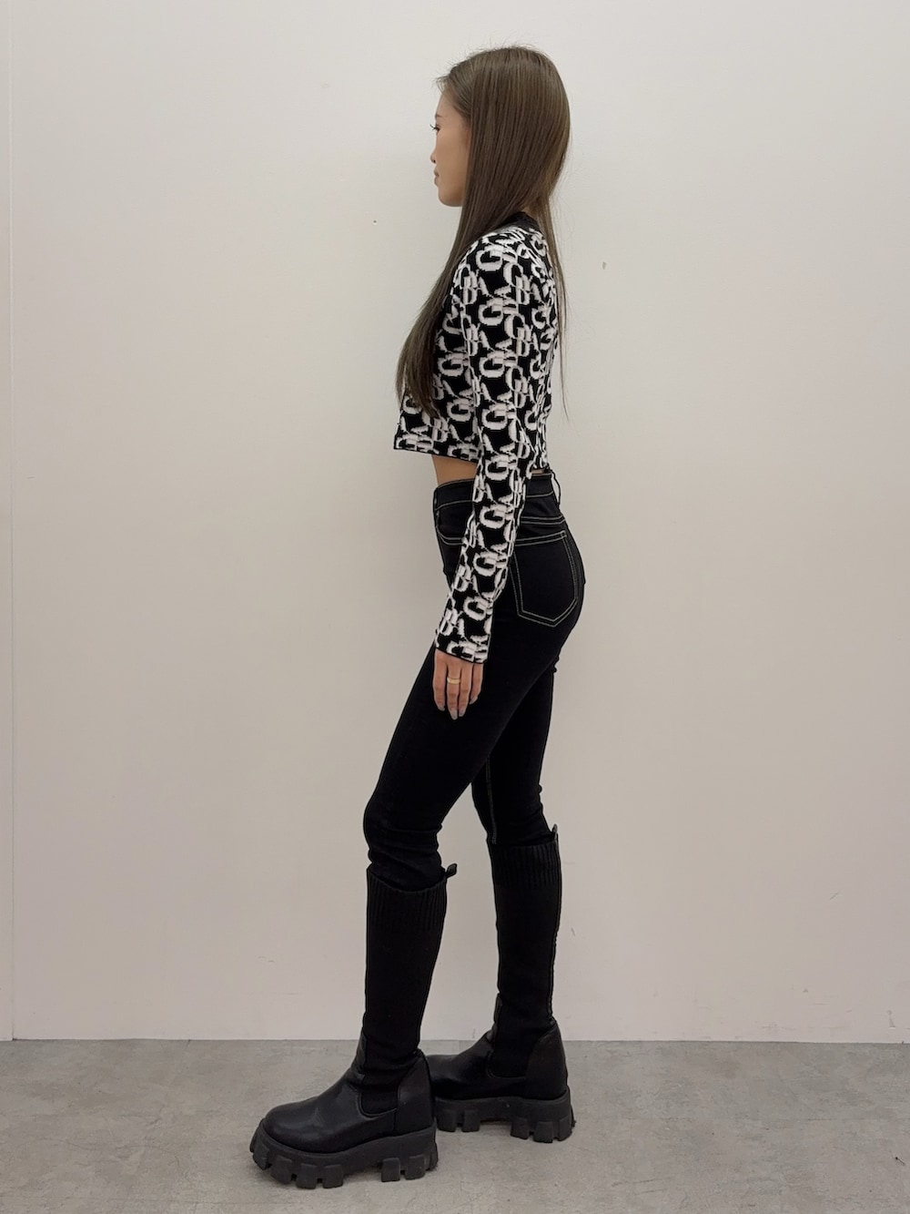 ブラック系のデニムパンツ、ブラック系のブーツ、ブラック系のニット/セーターを着用したレディースの秋コーディネートの2枚目の写真