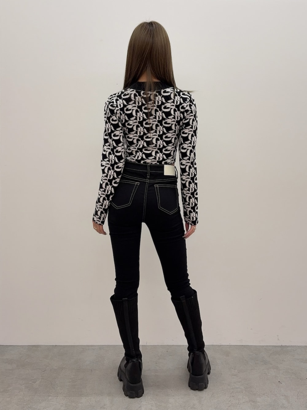 ブラック系のデニムパンツ、ブラック系のブーツ、ブラック系のニット/セーターを着用したレディースの秋コーディネートの3枚目の写真