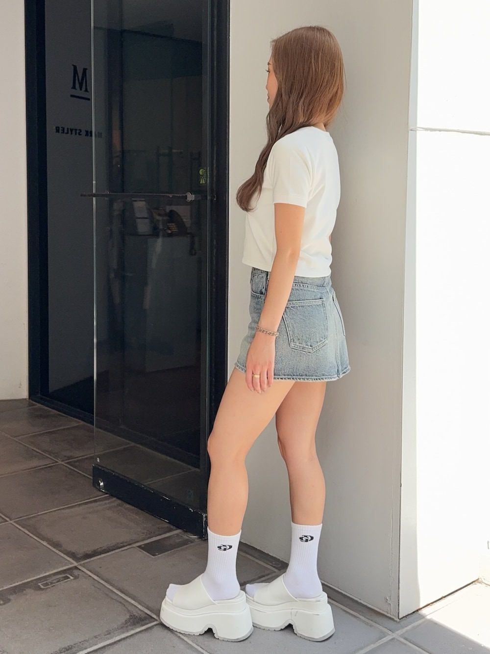 ホワイト系のTシャツ/カットソー、ブルー系のデニムスカート、ホワイト系のサンダルを着用したレディースの夏コーディネートの2枚目の写真