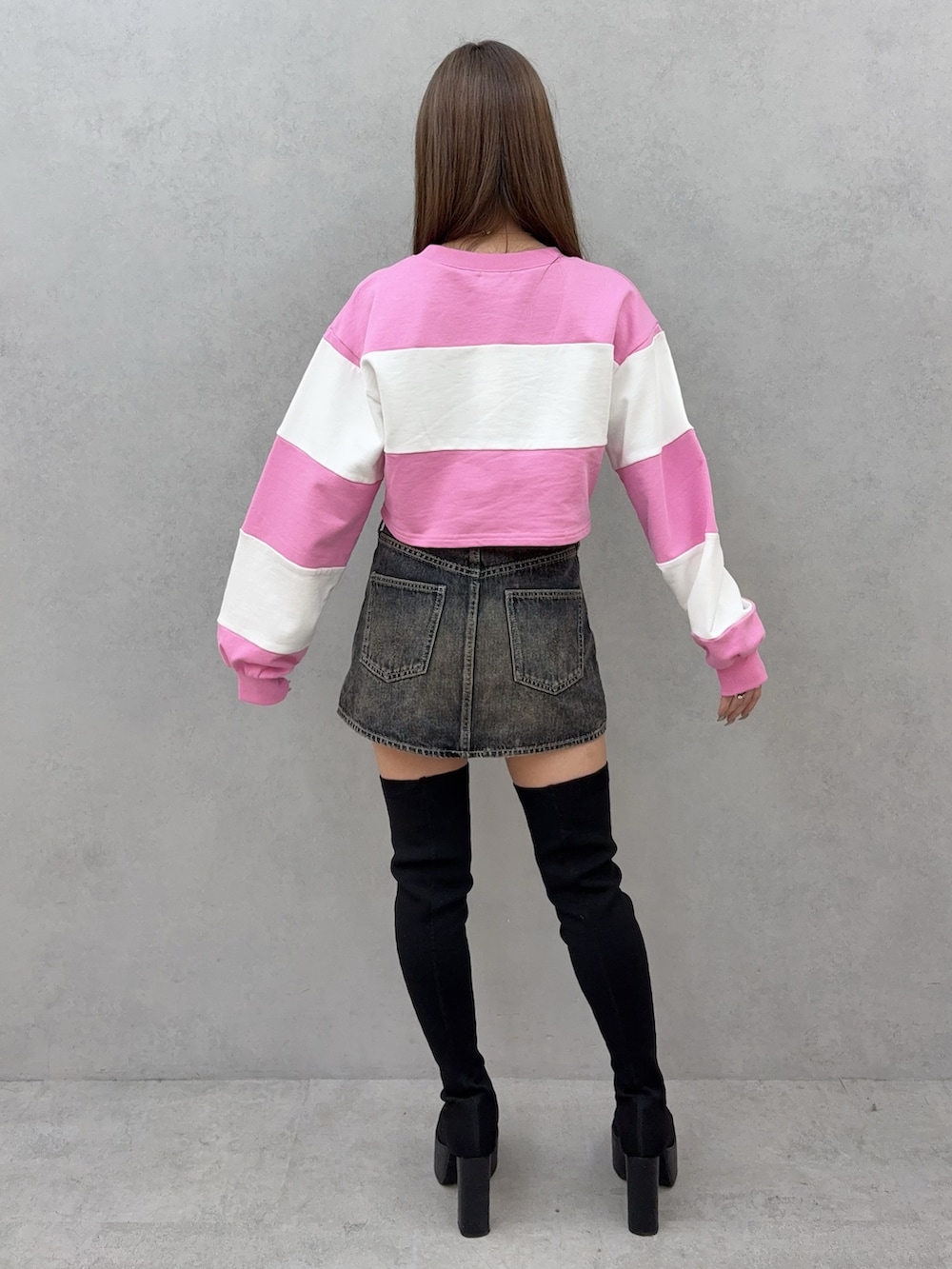 ブルー系のデニムスカート、ブラック系のブーツ、ピンク系のTシャツ/カットソーを着用したレディースの冬コーディネートの3枚目の写真