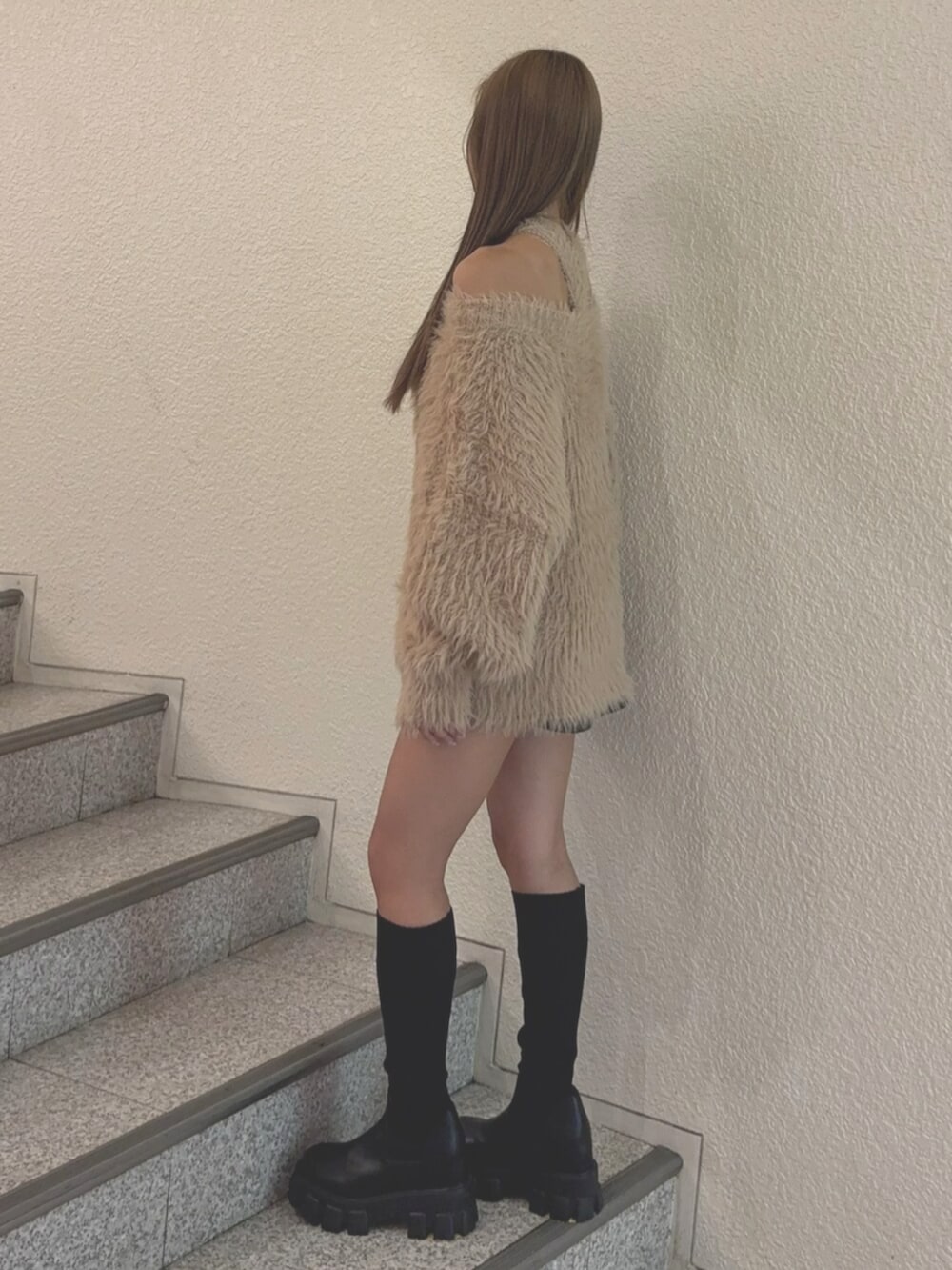 ブルー系のデニムスカート、ブラック系のブーツ、ベージュ系のニット/セーターを着用したレディースの秋コーディネートの3枚目の写真