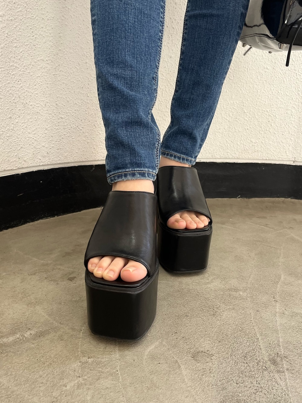 ブラック系のニット/セーター、ブルー系のデニムパンツ、ブラック系のサンダルを着用したレディースの夏コーディネートの7枚目の写真