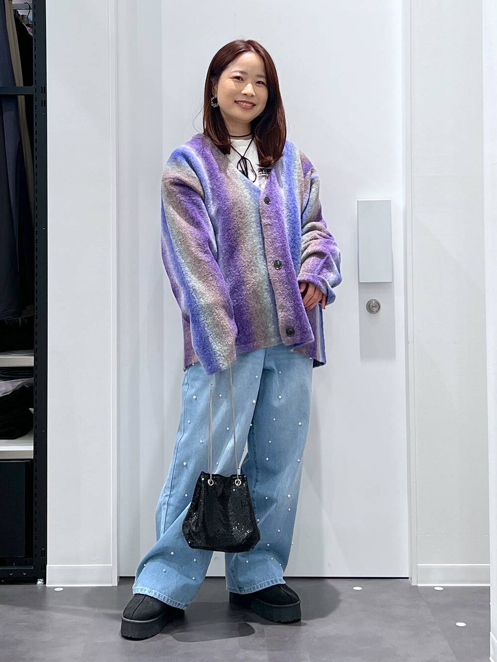 ブラック系のスリッポン、パープル系のカーディガン/ボレロ、ブルー系のデニムパンツを着用したレディースの冬コーディネートの2枚目の写真