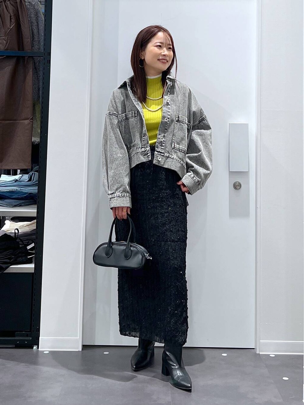 グリーン系のニット/セーター、ブラック系のスカート、ブラック系のブーツを着用したレディースの冬コーディネートの3枚目の写真