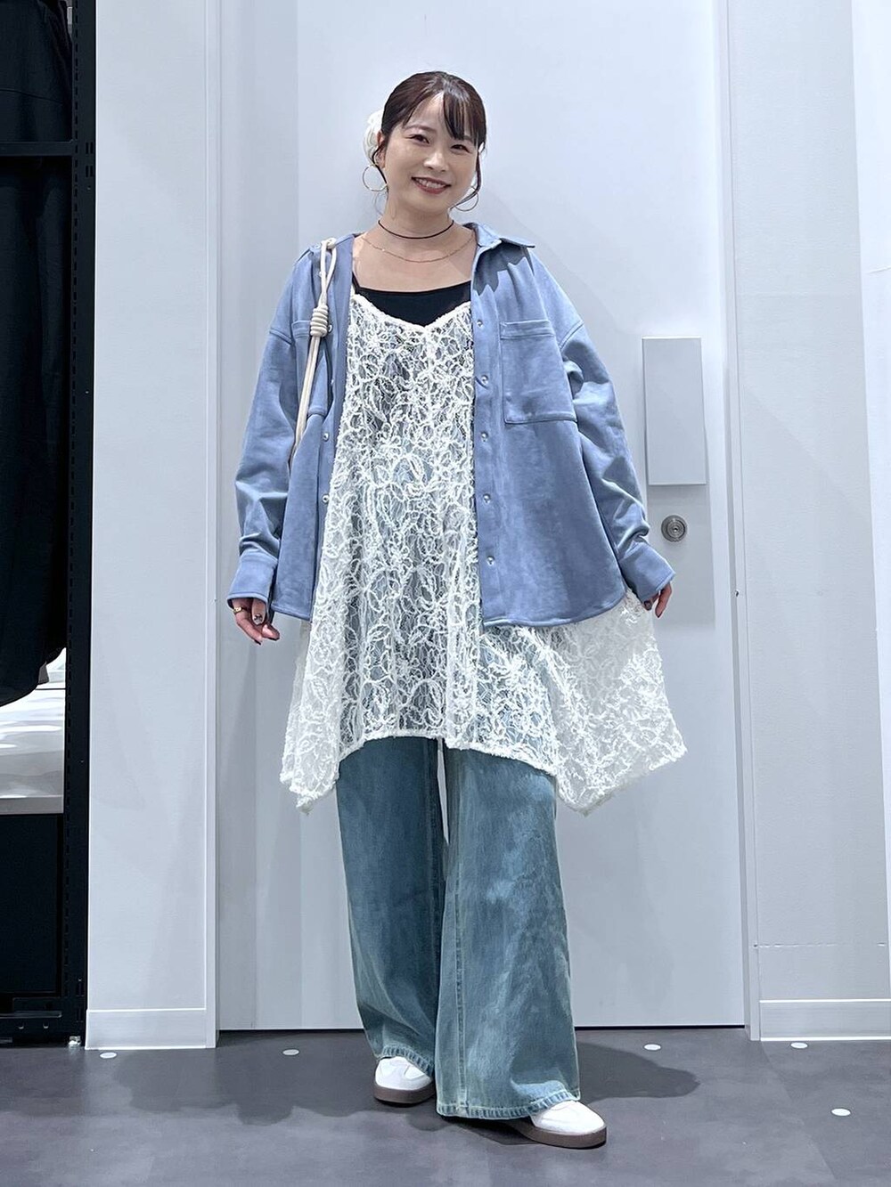 ホワイト系のスニーカー、ホワイト系のショルダーバッグ、ブルー系のデニムパンツを着用したレディースの秋コーディネートの4枚目の写真