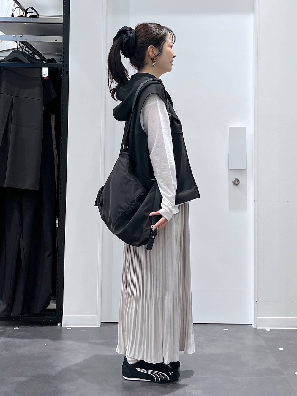 ブラック系のスニーカー、ブラック系のショルダーバッグ、ブラック系のベストを着用したレディースの春コーディネートの2枚目の写真