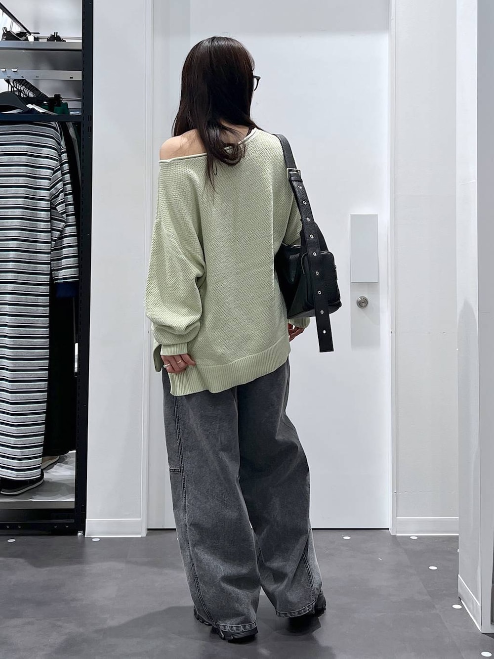 ブラック系のショルダーバッグ、ブラック系のスニーカー、グリーン系のニット/セーターを着用したレディースの春コーディネートの3枚目の写真