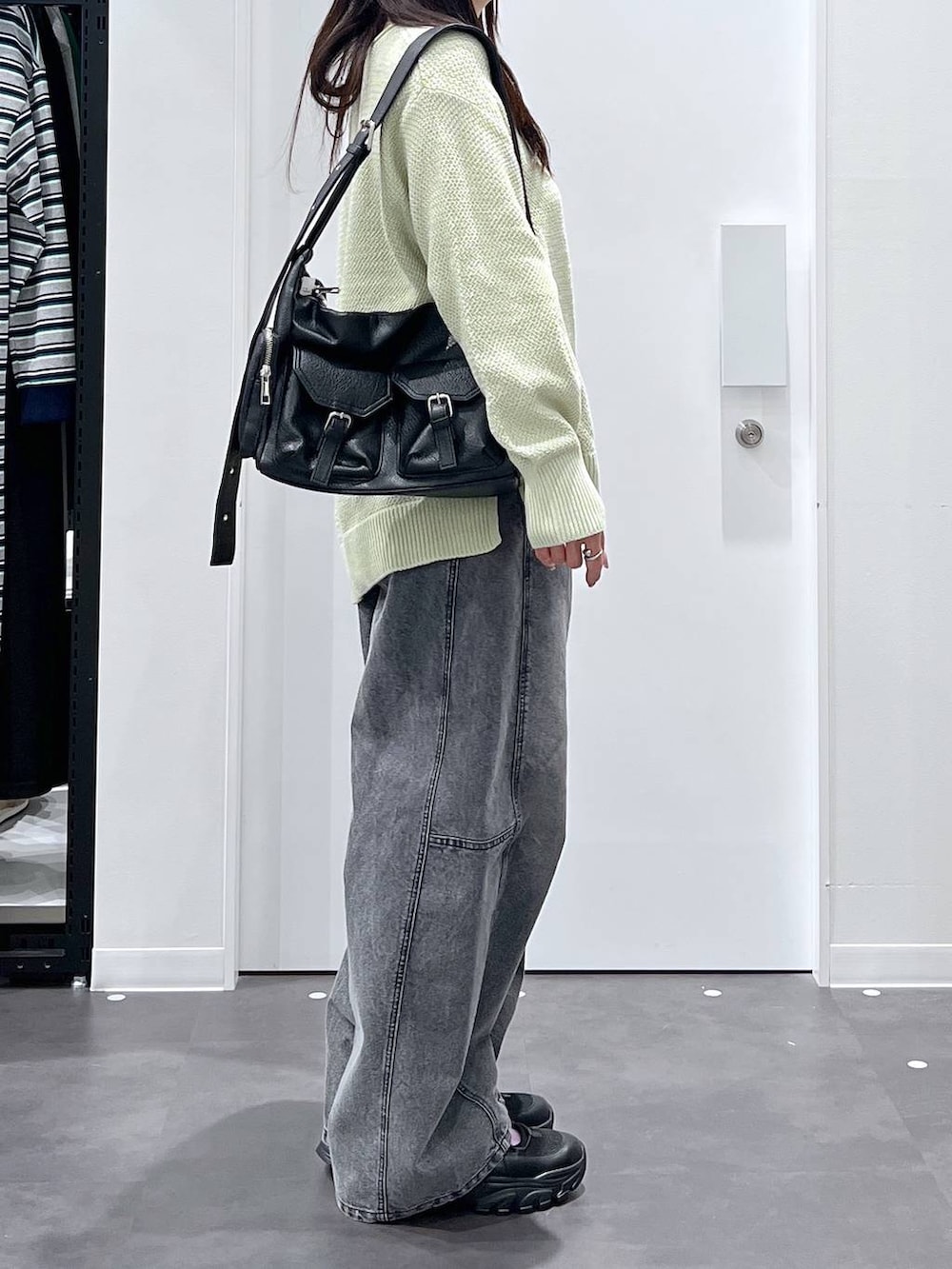 ブラック系のショルダーバッグ、ブラック系のスニーカー、グリーン系のニット/セーターを着用したレディースの春コーディネートの2枚目の写真
