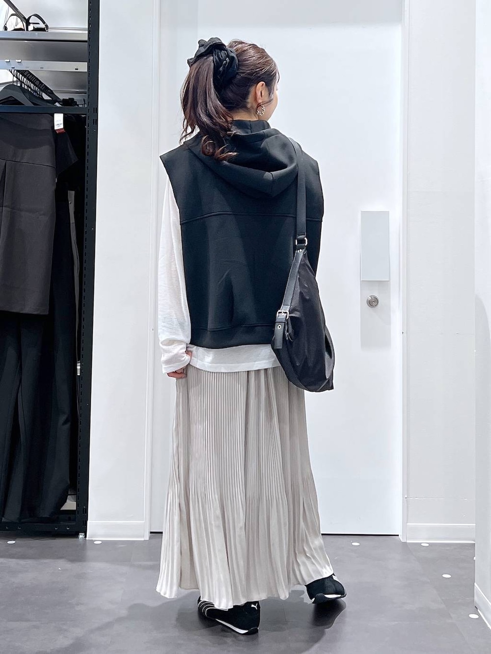 ブラック系のスニーカー、ブラック系のショルダーバッグ、ブラック系のベストを着用したレディースの春コーディネートの3枚目の写真