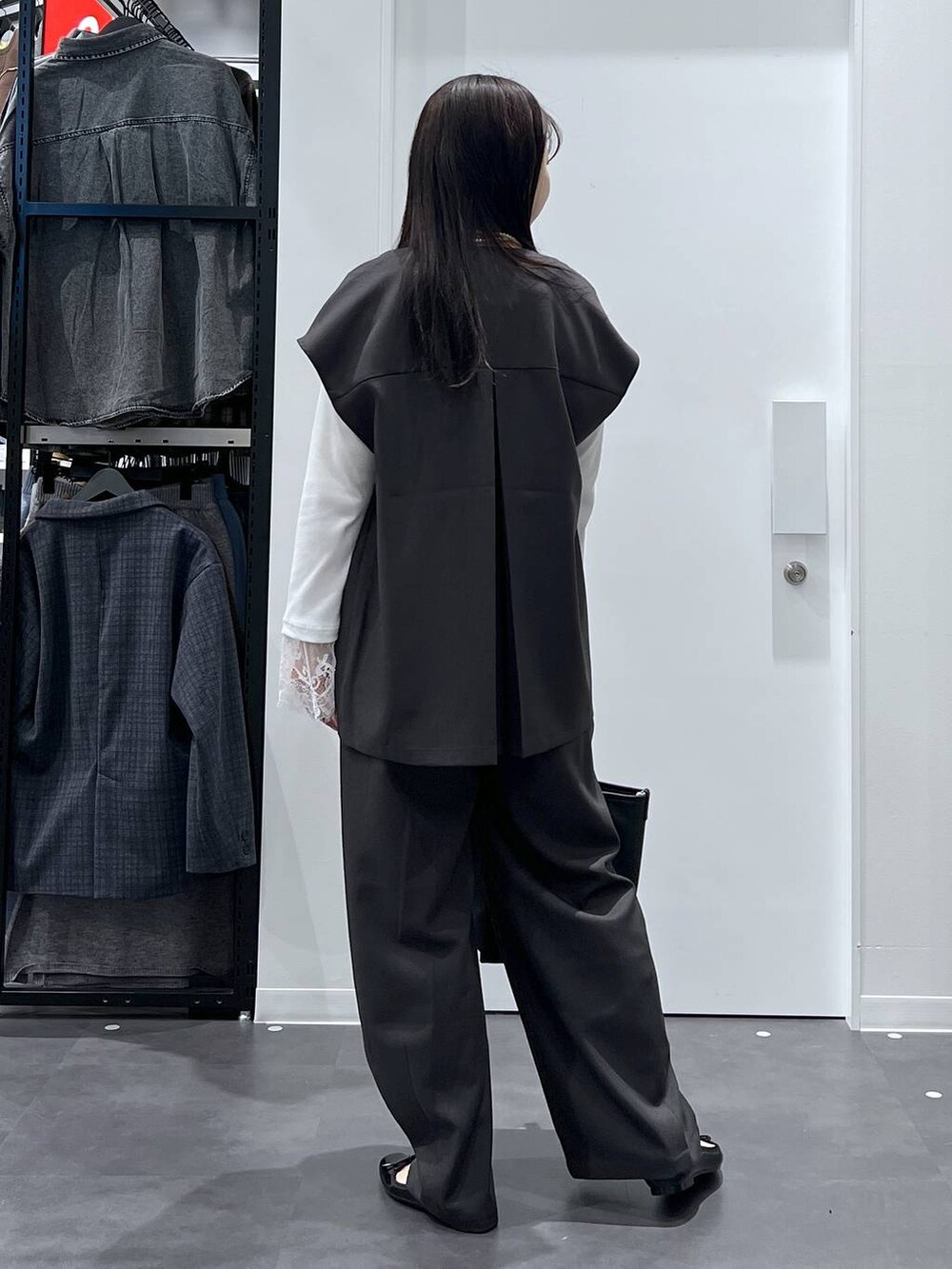 ブラック系のレインシューズ、ブラック系のトートバッグ、グレー系のベストを着用したレディースの冬コーディネートの3枚目の写真