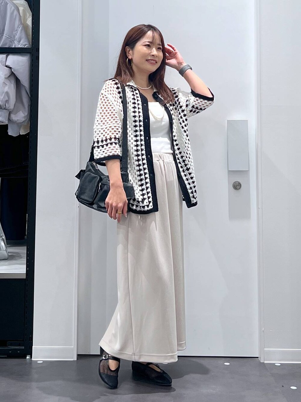 ホワイト系のキャミソール、ブラック系のショルダーバッグ、ベージュ系のスカートを着用したレディースの春コーディネートの2枚目の写真