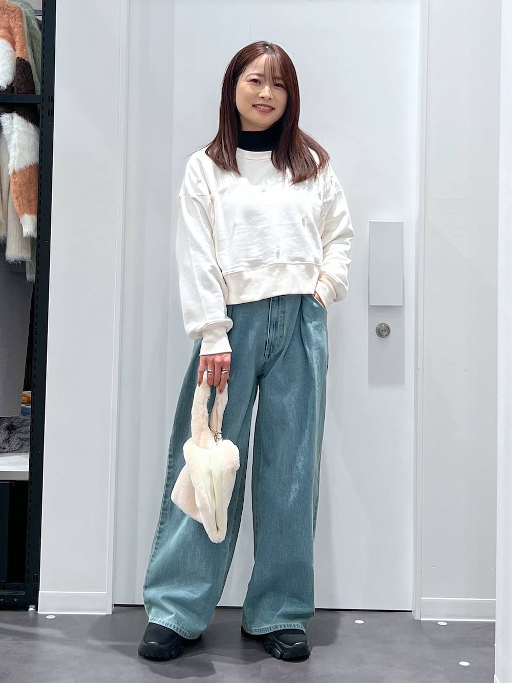 ホワイト系のショルダーバッグ、ブラック系のブーツ、ホワイト系のスウェットを着用したレディースの冬コーディネートの3枚目の写真