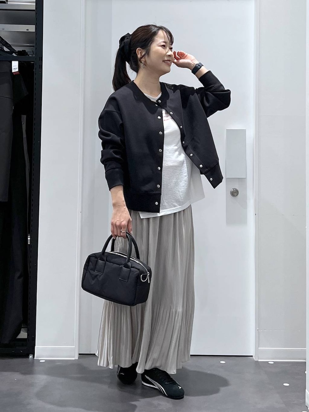 ブラック系のスニーカー、ブラック系のカーディガン/ボレロ、ベージュ系のスカートを着用したレディースの春コーディネートの6枚目の写真