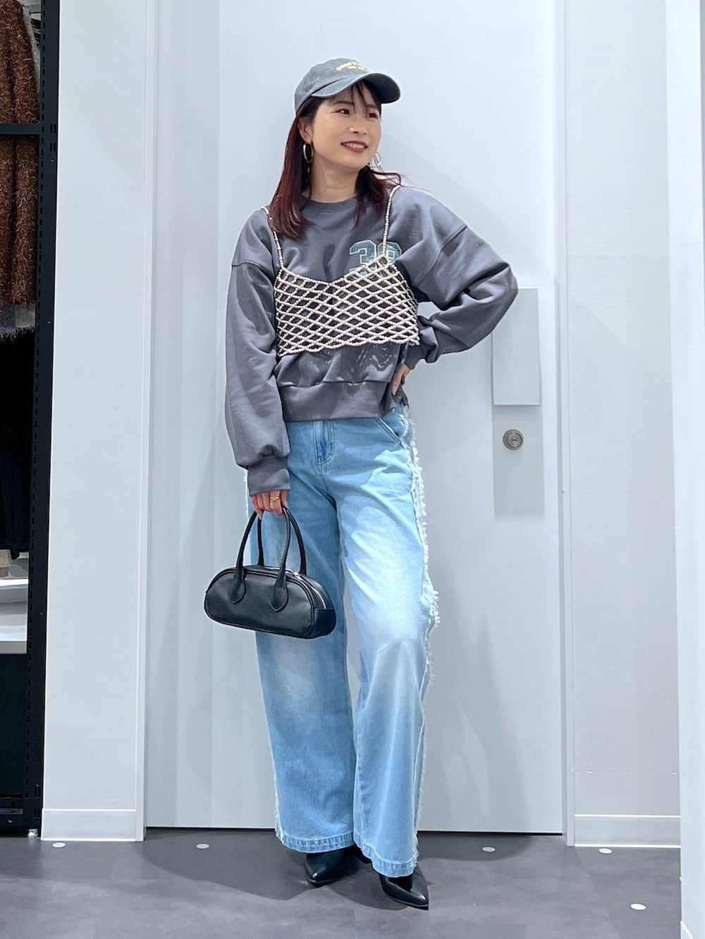 シルバー系のベスト、ブラック系のブーツ、ブラック系のボストンバッグを着用したレディースの冬コーディネートの2枚目の写真