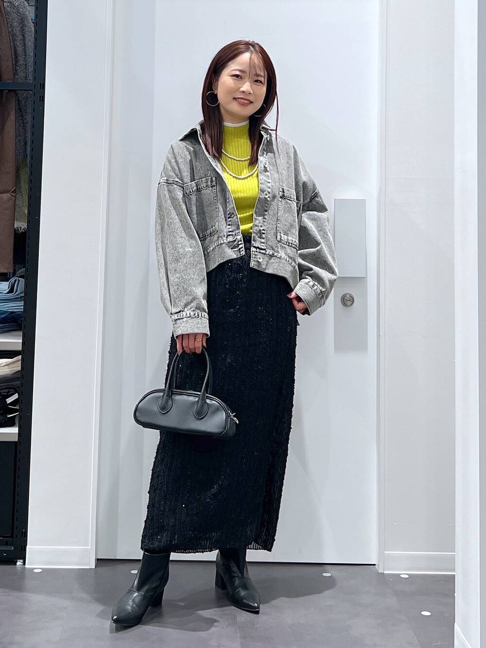 グリーン系のニット/セーター、ブラック系のスカート、ブラック系のブーツを着用したレディースの冬コーディネートの2枚目の写真