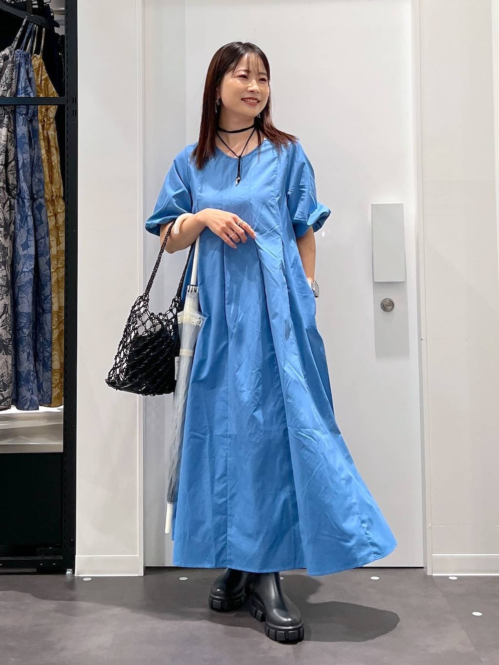 ブラック系のかごバッグ、ブラック系のレインシューズ、ブルー系のワンピースを着用したレディースの春コーディネートの4枚目の写真