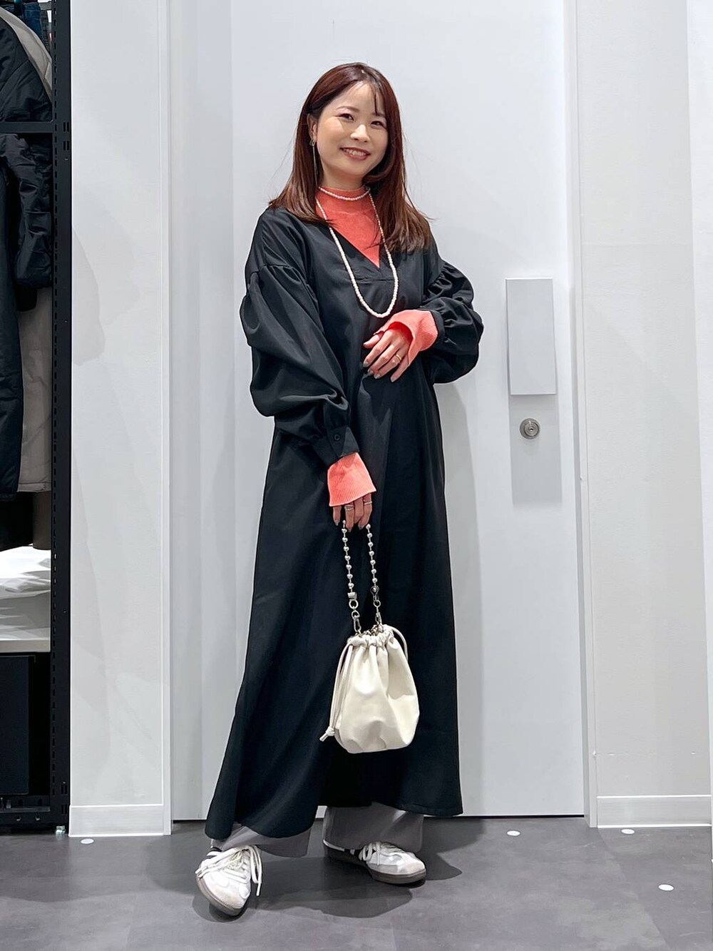 ベージュ系のショルダーバッグ、オレンジ系のニット/セーター、グレー系のその他パンツを着用したレディースの春コーディネートの2枚目の写真