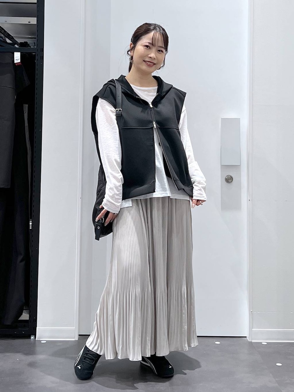 ブラック系のスニーカー、ブラック系のショルダーバッグ、ブラック系のベストを着用したレディースの春コーディネートの5枚目の写真