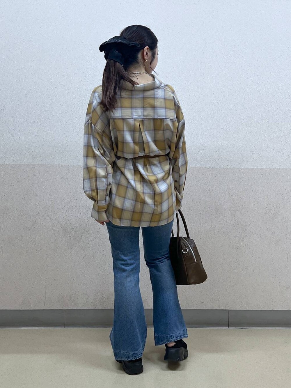 ブルー系のデニムパンツ、イエロー系のシャツ/ブラウス、ブラック系のスニーカーを着用したレディースの夏コーディネートの3枚目の写真