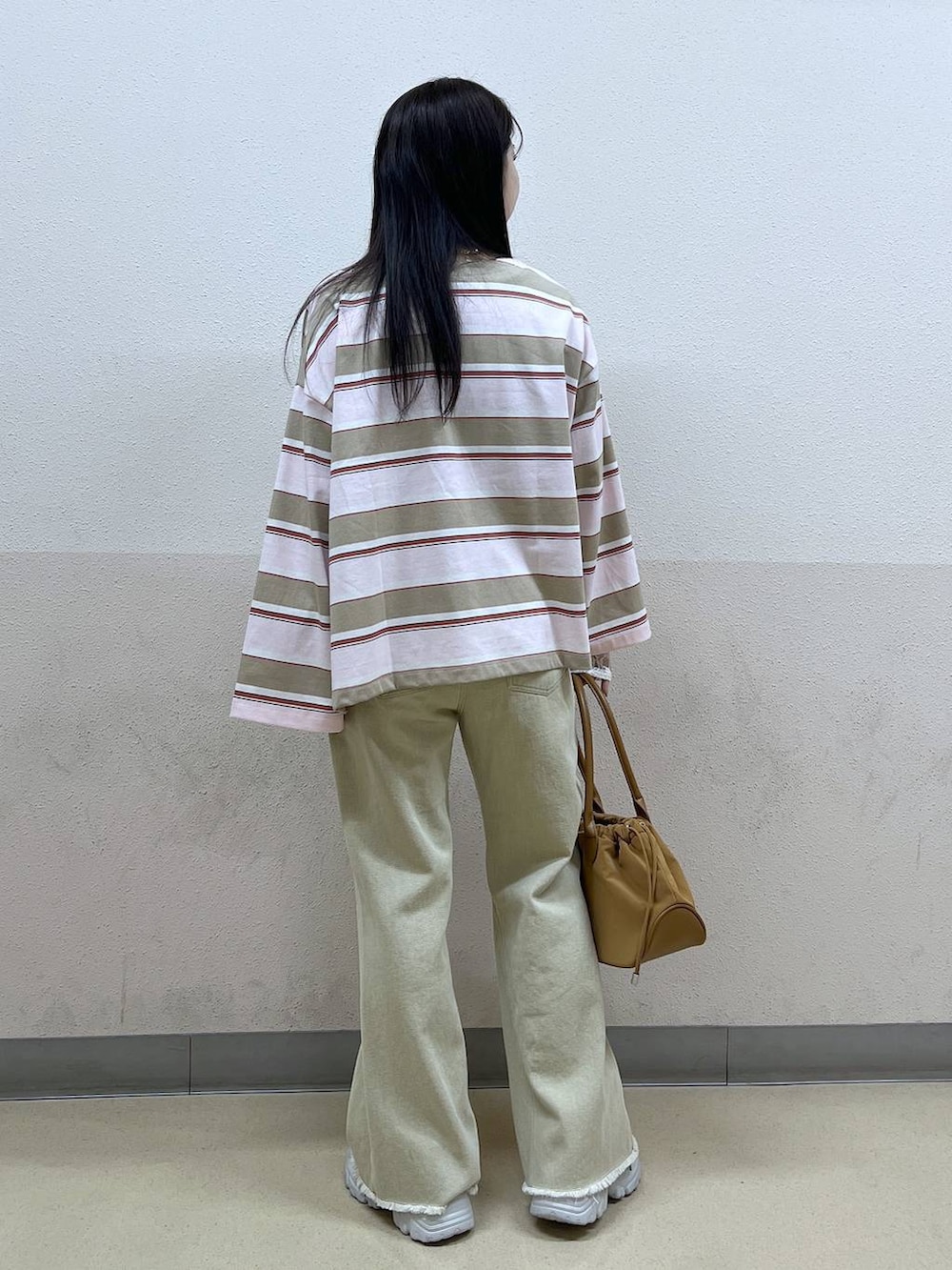 ホワイト系のTシャツ/カットソー、ブラウン系のハンドバッグ、ベージュ系のデニムパンツを着用したレディースの冬コーディネートの3枚目の写真