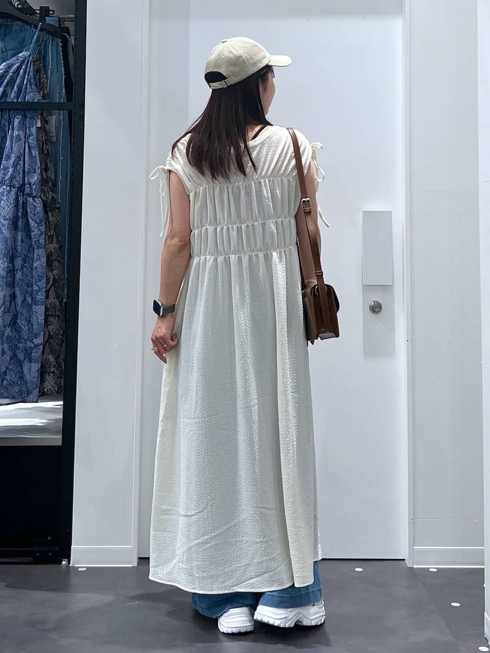 ホワイト系のスニーカー、ブラウン系のショルダーバッグ、ブルー系のデニムパンツを着用したレディースの夏コーディネートの3枚目の写真