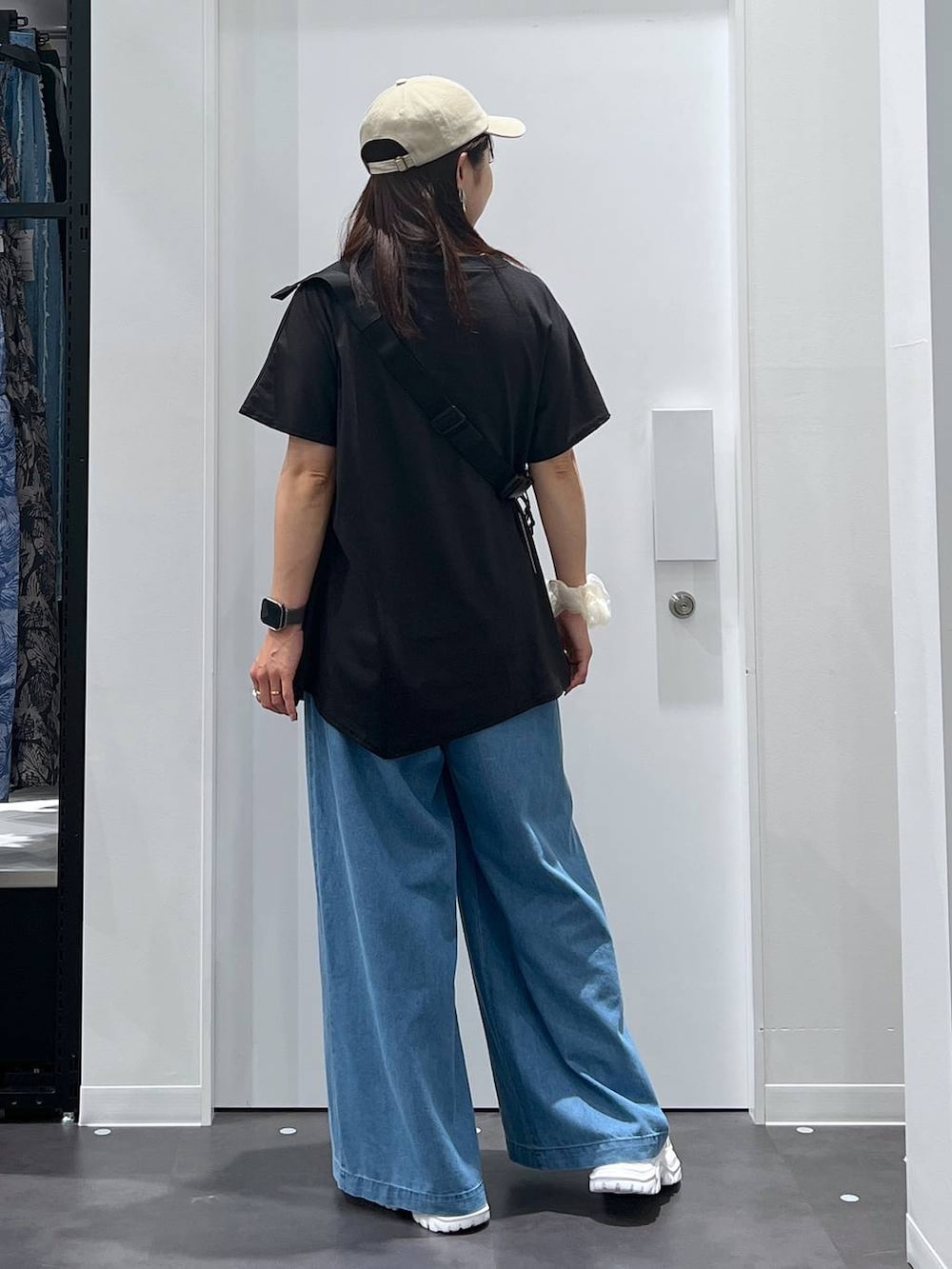 シルバー系のボディバッグ/ウエストポーチ、ホワイト系のスニーカー、ブルー系のデニムパンツを着用したレディースの夏コーディネートの3枚目の写真