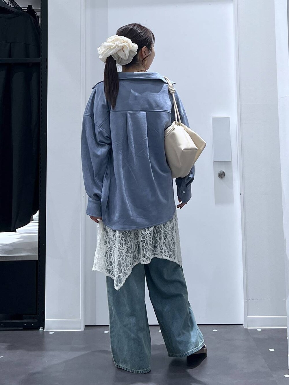 ホワイト系のスニーカー、ホワイト系のショルダーバッグ、ブルー系のデニムパンツを着用したレディースの秋コーディネートの3枚目の写真