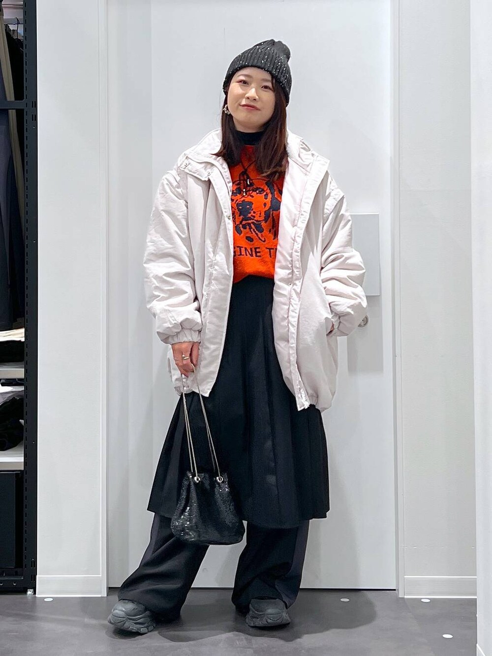 オレンジ系のニット/セーター、グレー系のその他アウター、ブラック系のブーツを着用したレディースの冬コーディネートの4枚目の写真