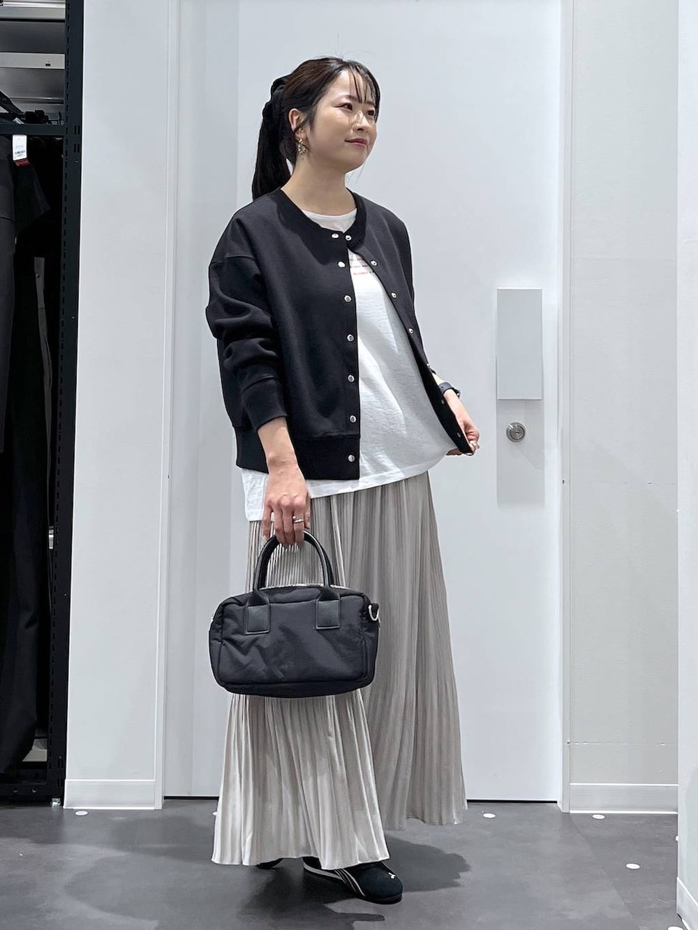 ブラック系のスニーカー、ブラック系のカーディガン/ボレロ、ベージュ系のスカートを着用したレディースの春コーディネートの5枚目の写真