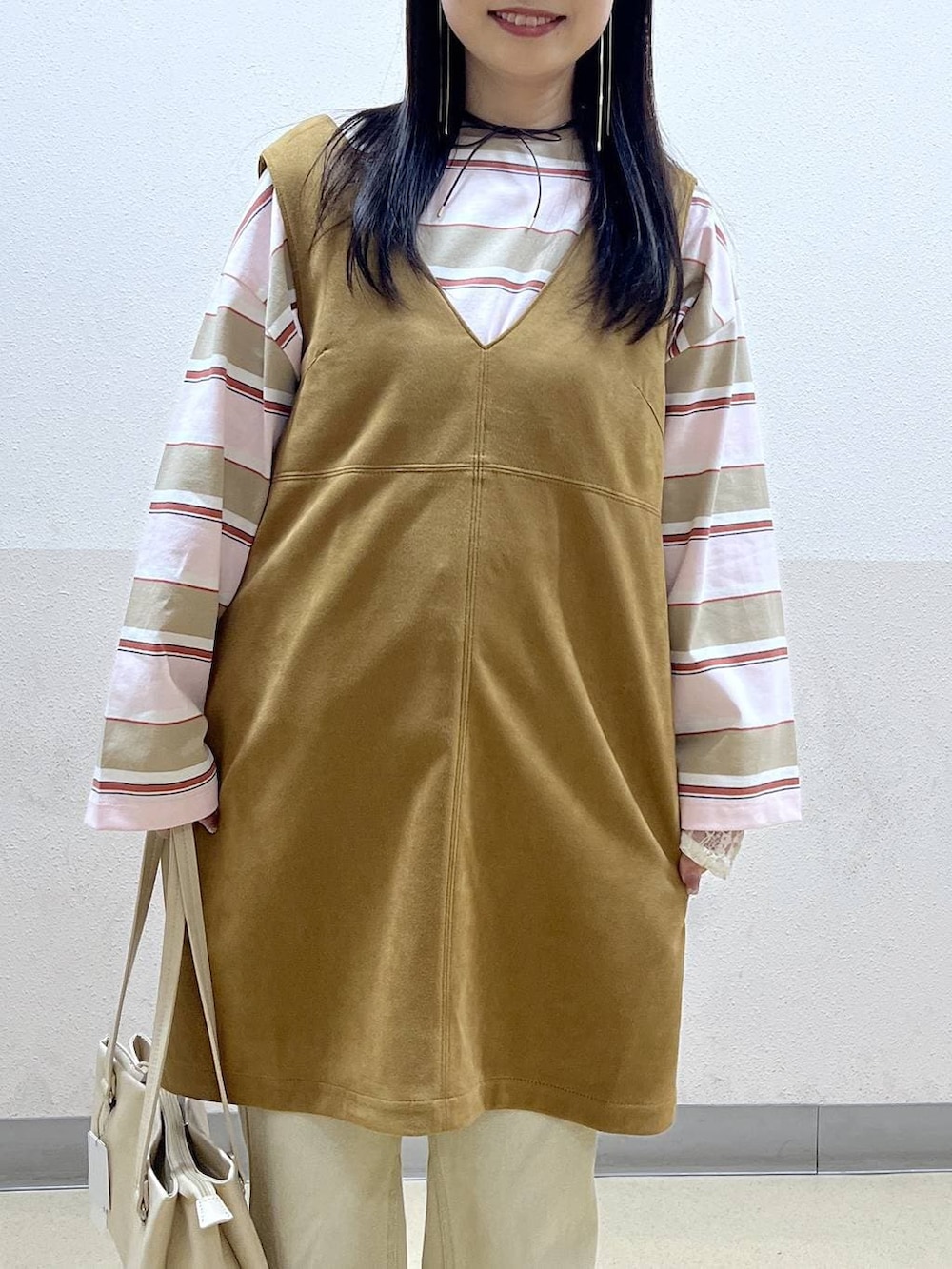 ホワイト系のハンドバッグ、イエロー系のワンピース、ベージュ系のデニムパンツを着用したレディースの冬コーディネートの5枚目の写真