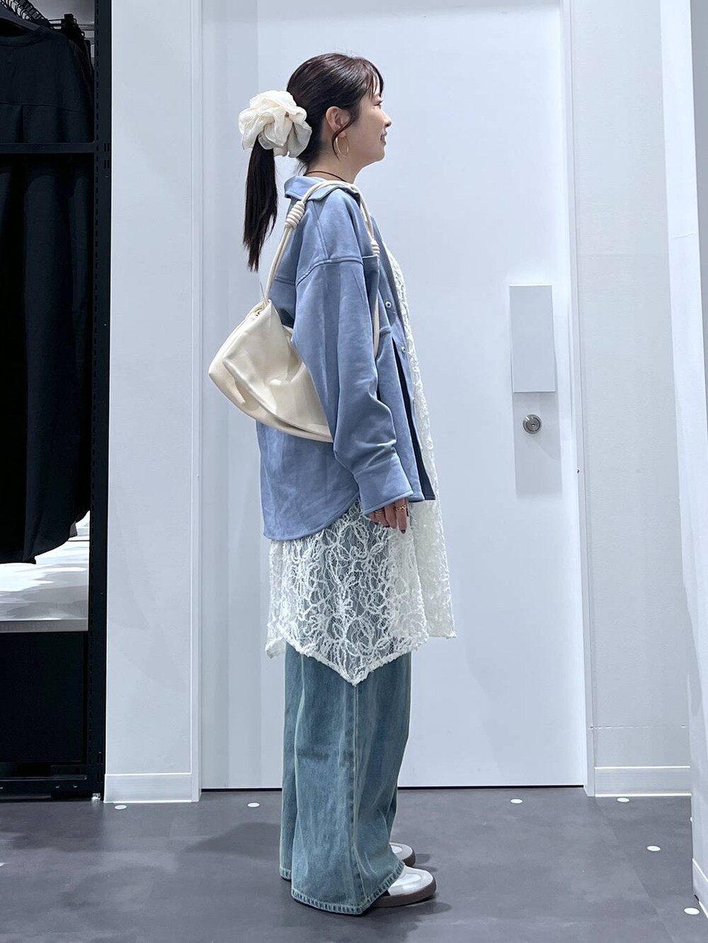 ホワイト系のスニーカー、ホワイト系のショルダーバッグ、ブルー系のデニムパンツを着用したレディースの秋コーディネートの2枚目の写真