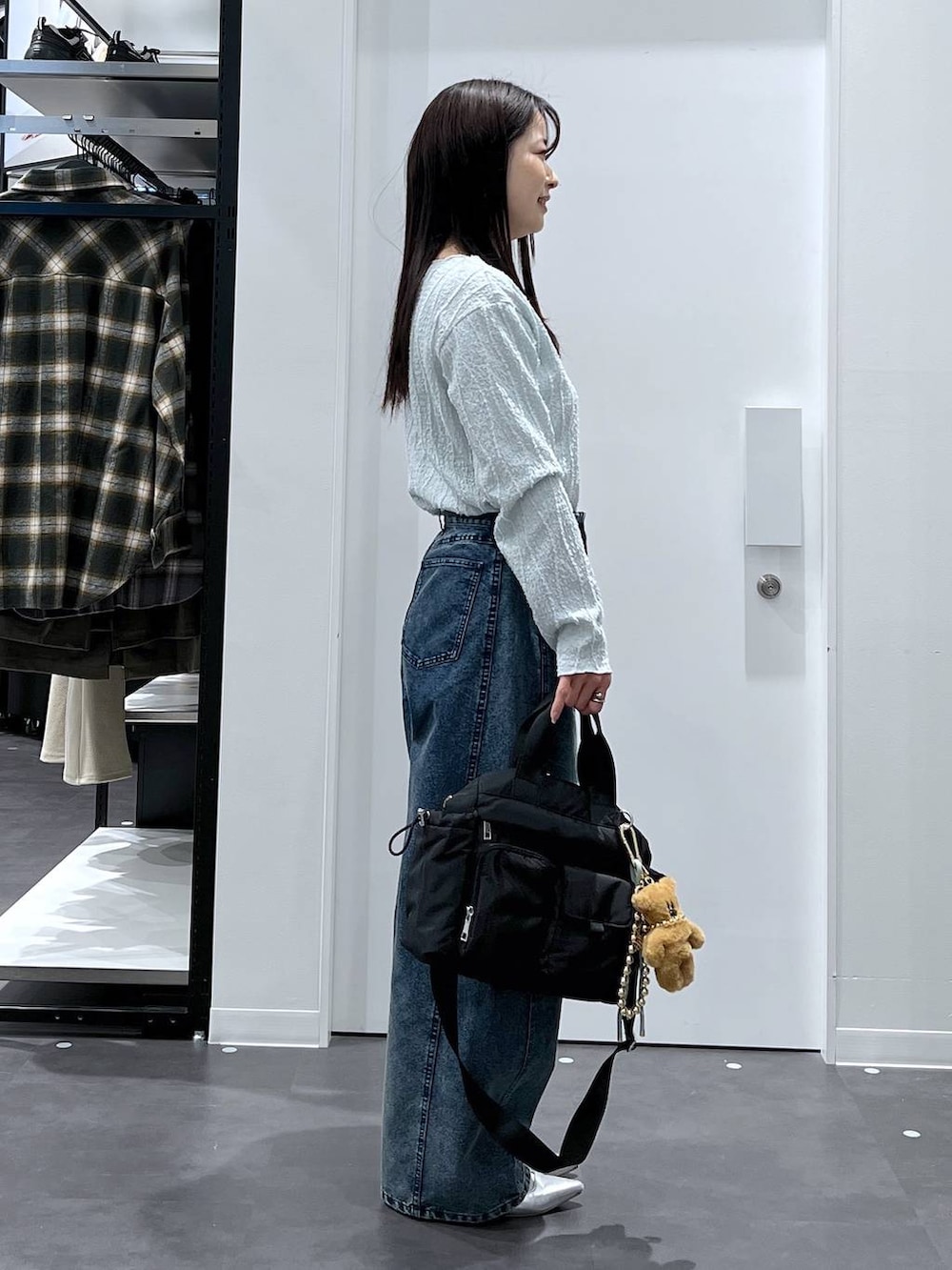 シルバー系のパンプス、ブラック系のトートバッグ、ブルー系のデニムパンツを着用したレディースの春コーディネートの3枚目の写真