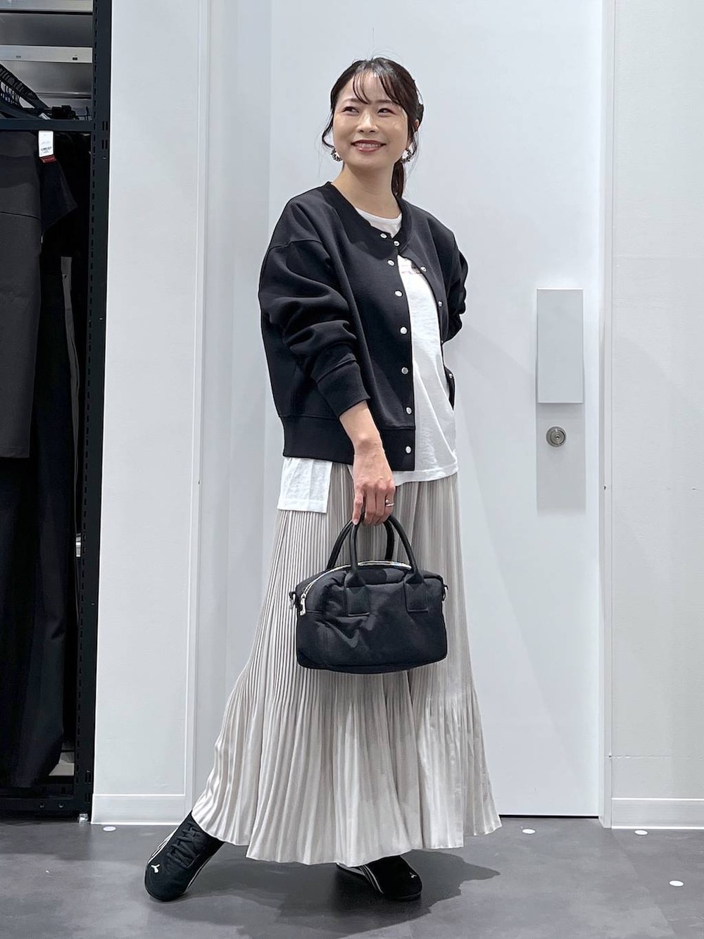 ブラック系のスニーカー、ブラック系のカーディガン/ボレロ、ベージュ系のスカートを着用したレディースの春コーディネートの4枚目の写真