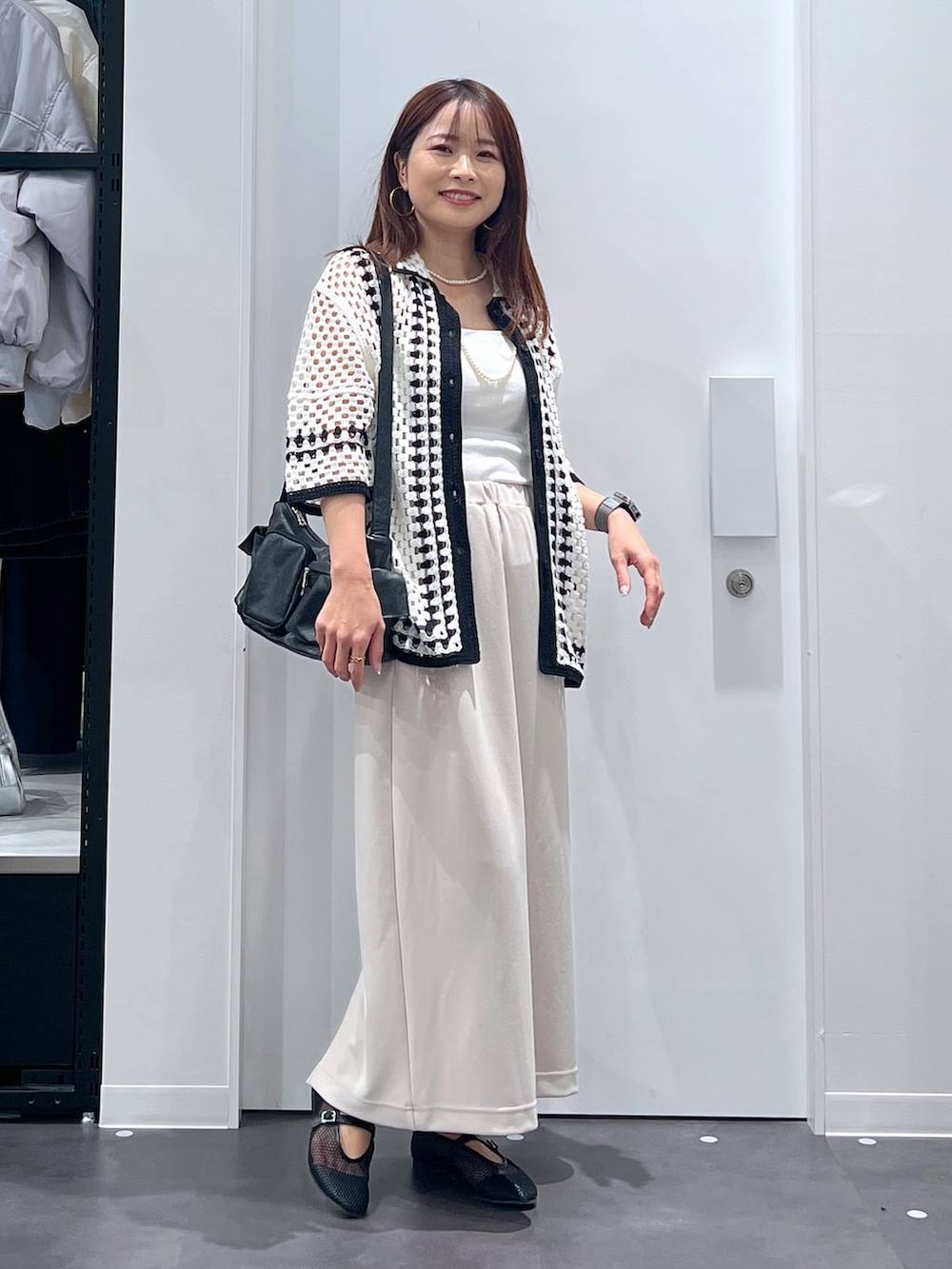 ホワイト系のキャミソール、ブラック系のショルダーバッグ、ベージュ系のスカートを着用したレディースの春コーディネートの4枚目の写真