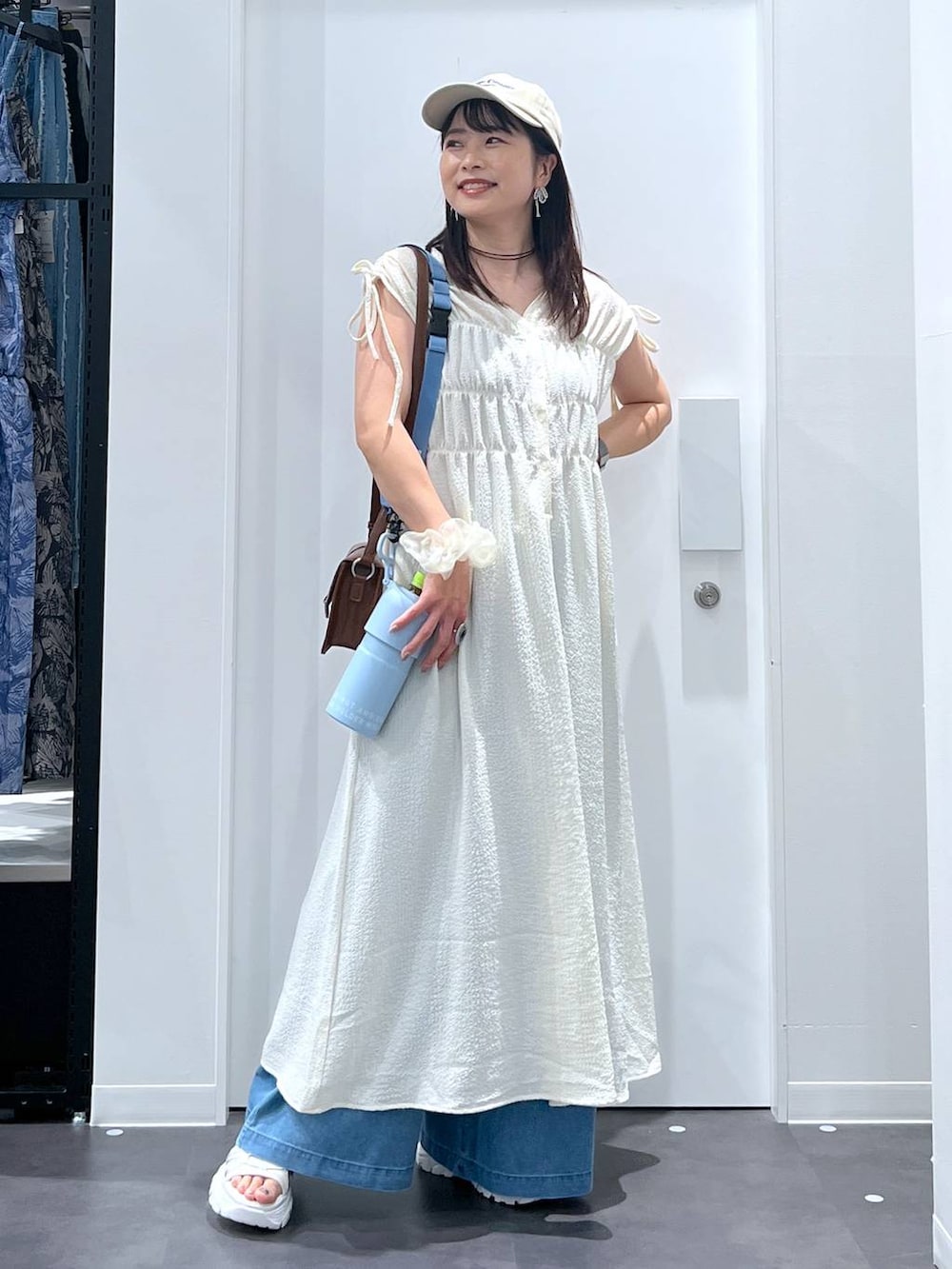 ホワイト系のスニーカー、ブラウン系のショルダーバッグ、ブルー系のデニムパンツを着用したレディースの夏コーディネートの4枚目の写真