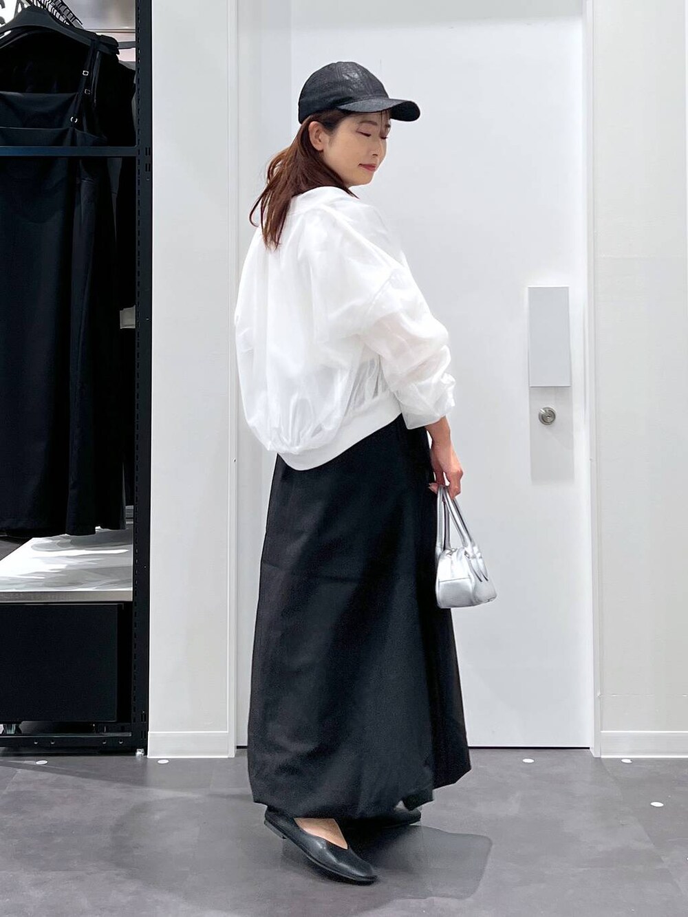 シルバー系のボストンバッグ、ブラック系のパンプス、ブラック系のスカートを着用したレディースの春コーディネートの2枚目の写真