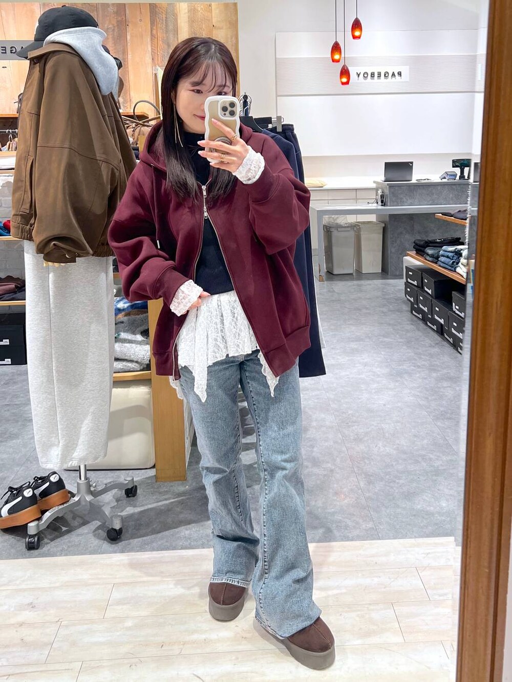 ブラウン系のパーカー、ブラウン系のスリッポン、ホワイト系のチュニックを着用したレディースの冬コーディネートの3枚目の写真