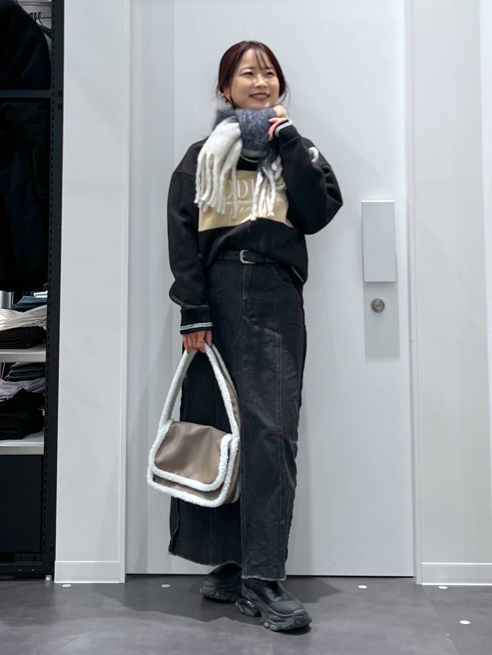 ブラック系のブーツ、ベージュ系のショルダーバッグ、ブラック系のデニムスカートを着用したレディースの冬コーディネートの3枚目の写真