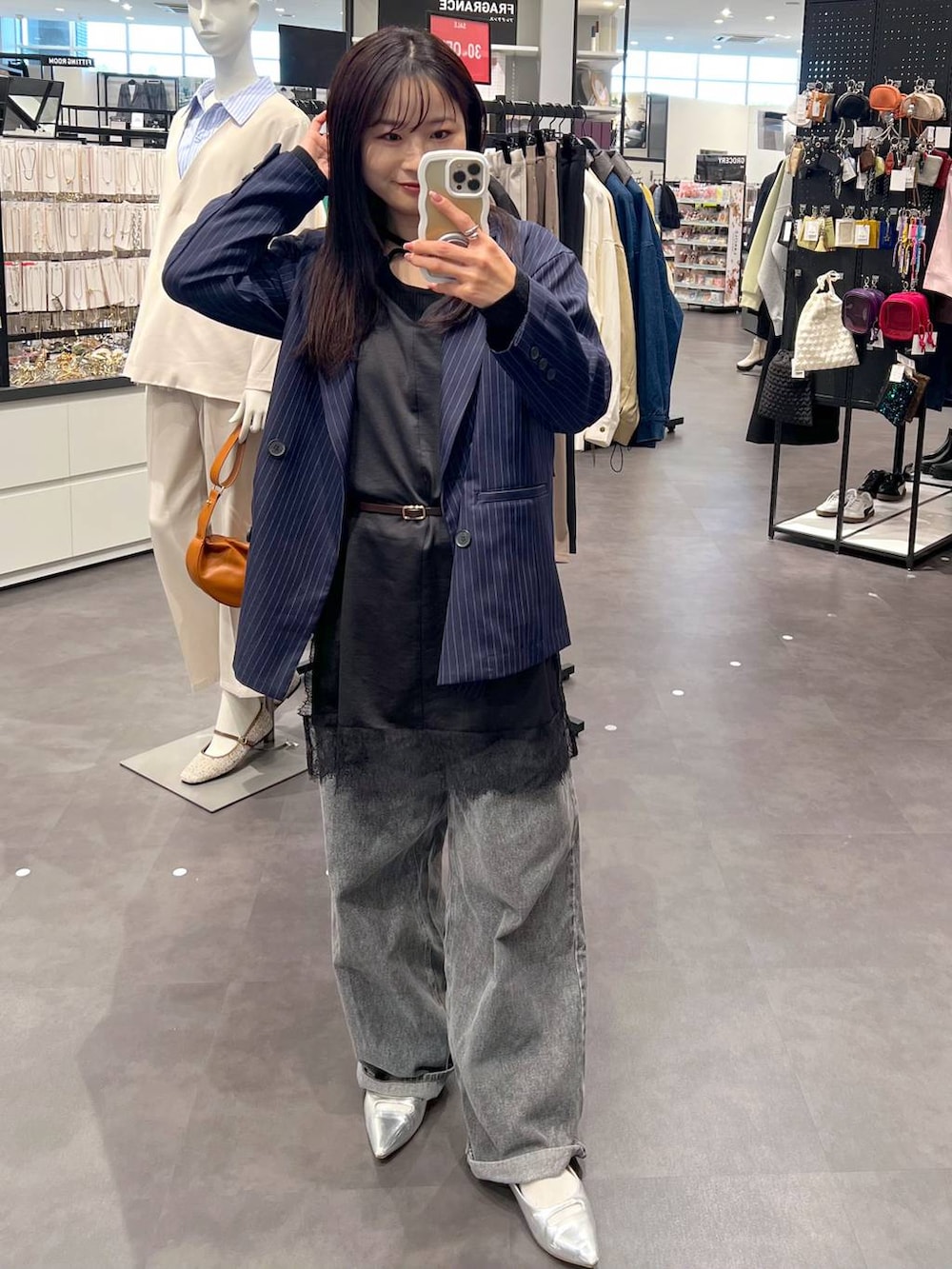 シルバー系のパンプス、ブラック系のデニムパンツ、ブルー系のテーラードジャケットを着用したレディースの冬コーディネートの2枚目の写真