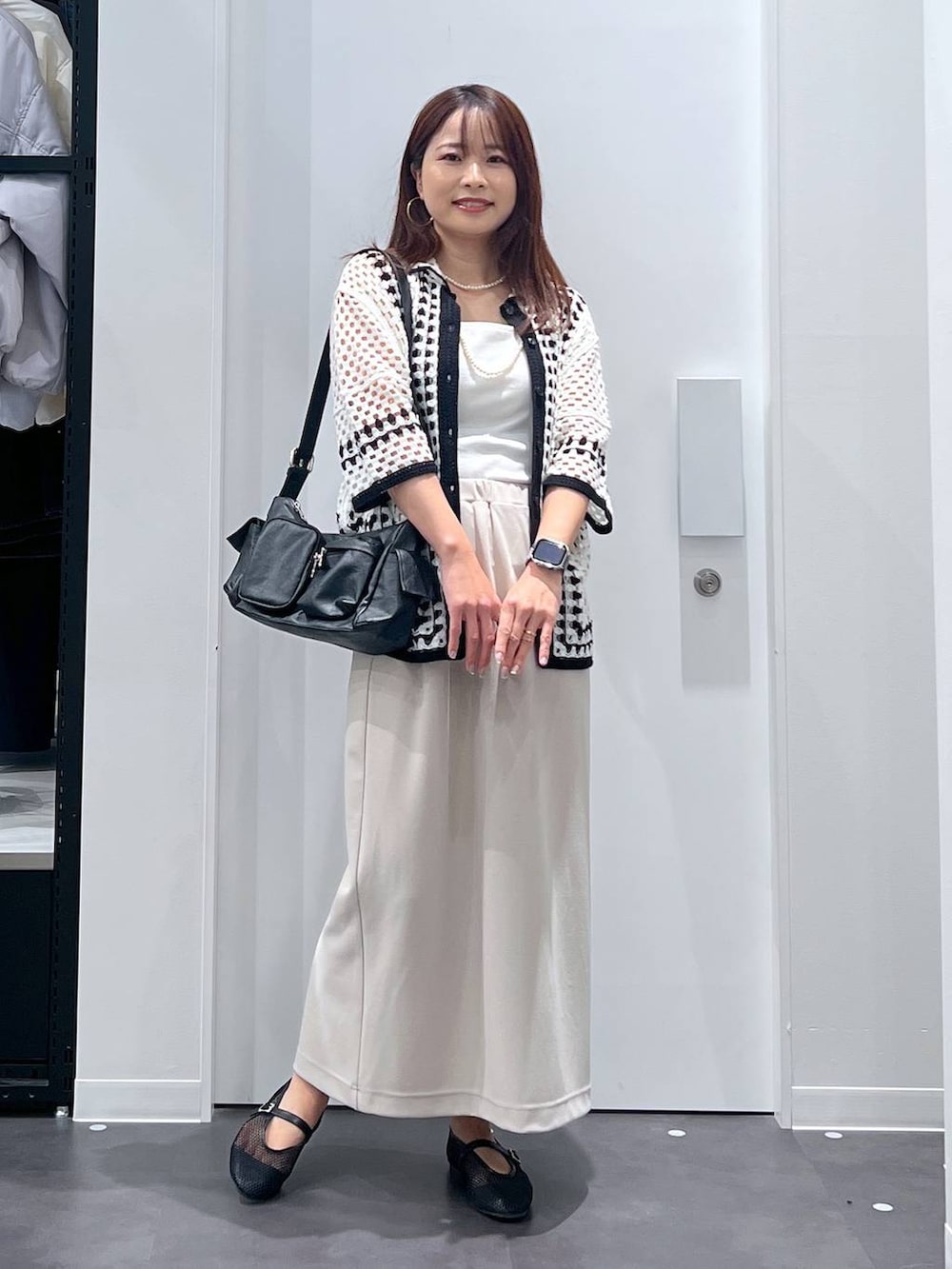 ホワイト系のキャミソール、ブラック系のショルダーバッグ、ベージュ系のスカートを着用したレディースの春コーディネートの3枚目の写真