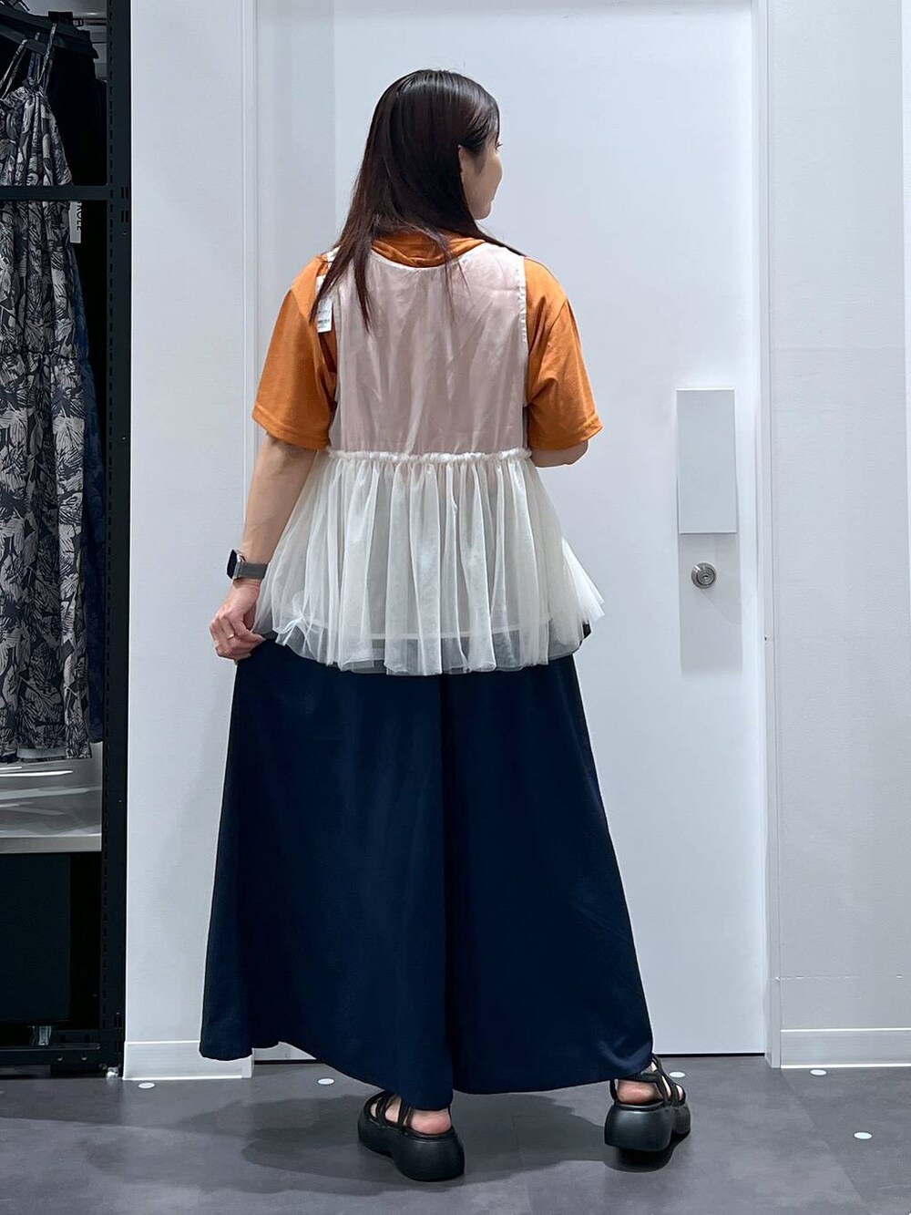 ブラック系のサンダル、オレンジ系のTシャツ/カットソー、ベージュ系のベストを着用したレディースの夏コーディネートの3枚目の写真