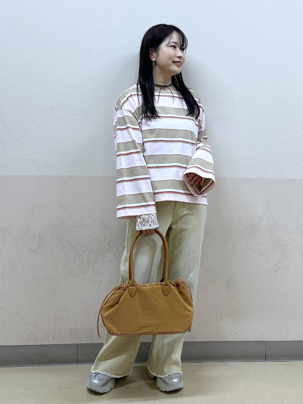 ホワイト系のTシャツ/カットソー、ブラウン系のハンドバッグ、ベージュ系のデニムパンツを着用したレディースの冬コーディネートの6枚目の写真